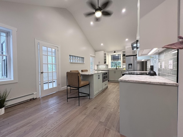 220 W Rd, Colchester, CT 06415 - kitchen with baseboard heating, a breakfast bar area, a ceiling fan, light wood finished floors, and high vaulted ceiling