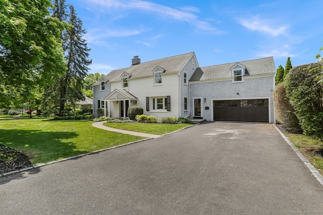 shingle-style home with driveway, a front lawn, and a chimney