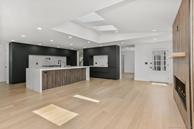 32 Pine Hill Ave, Norwalk, CT 06855 - unfurnished living room featuring a skylight, light wood-style floors, a lit fireplace, and recessed lighting