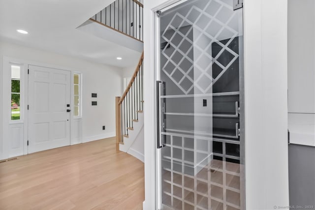 foyer featuring stairs, light wood-type flooring, recessed lighting, and baseboards