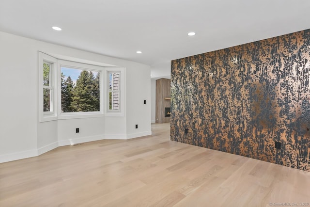 spare room featuring light wood-type flooring, recessed lighting, and baseboards
