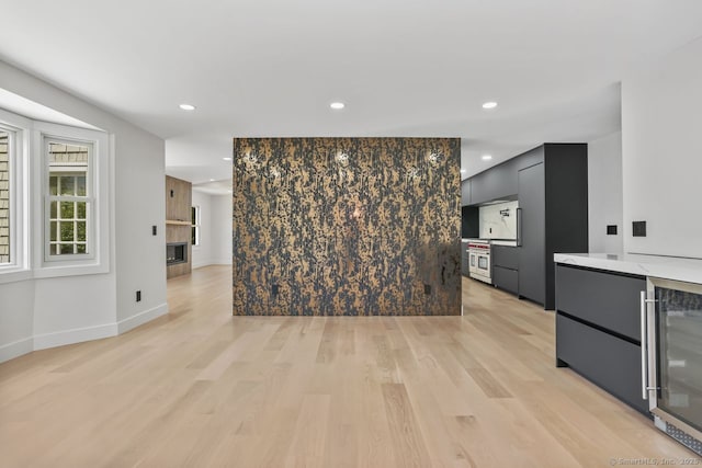 unfurnished living room with recessed lighting, light wood-type flooring, wine cooler, and baseboards