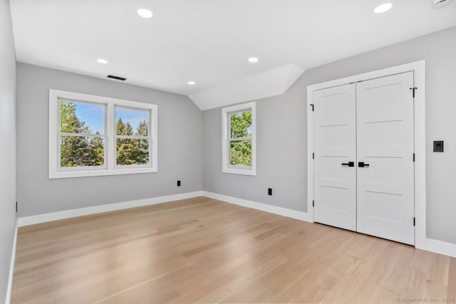 unfurnished bedroom featuring light wood-type flooring, recessed lighting, baseboards, vaulted ceiling, and a closet