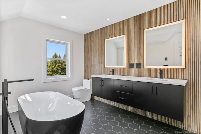bathroom featuring a freestanding bath, double vanity, toilet, recessed lighting, and tile patterned floors
