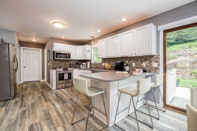 18 Tunnel Rd, Roxbury, CT 06783 - kitchen with appliances with stainless steel finishes, a peninsula, a breakfast bar area, light wood finished floors, and recessed lighting