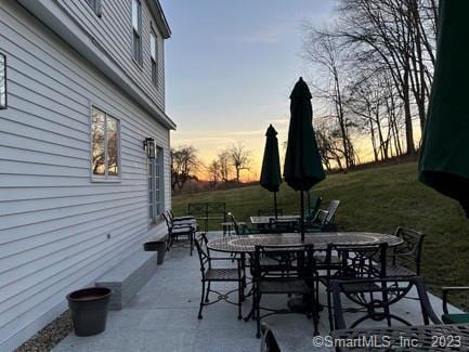 patio terrace at dusk featuring a yard and outdoor dining area