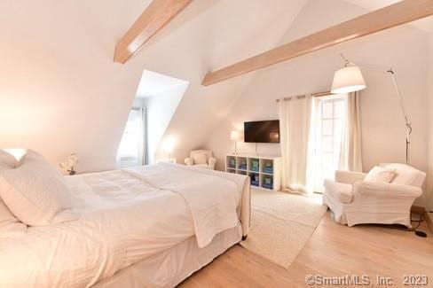 bedroom featuring multiple windows, vaulted ceiling with beams, and wood finished floors