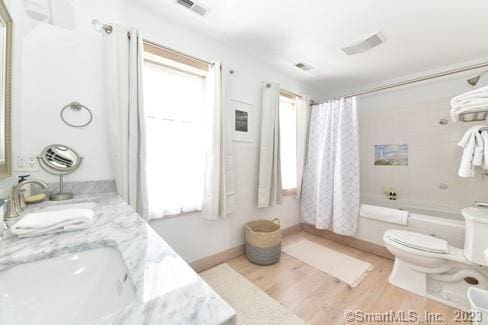 full bathroom featuring shower / bath combo, double vanity, visible vents, toilet, and wood finished floors
