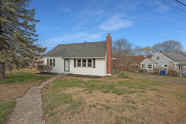 136 Cooper Dr, Waterbury, CT 06704 - view of front of house featuring a front yard, a shingled roof, and a chimney