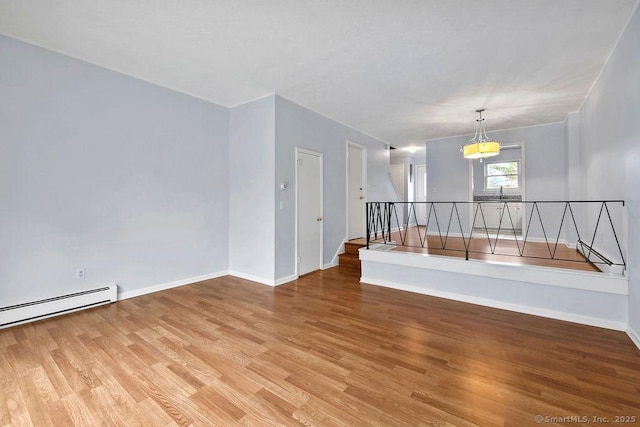 spare room with light wood-style flooring, a baseboard radiator, and baseboards