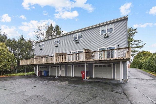 rear view of house featuring an attached garage, aphalt driveway, and a deck