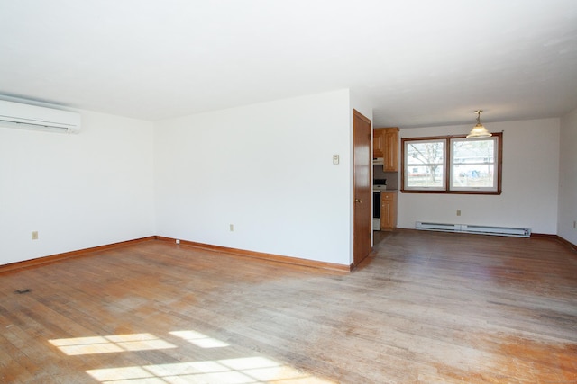 spare room featuring a wall mounted air conditioner, baseboards, light wood-type flooring, and a baseboard radiator