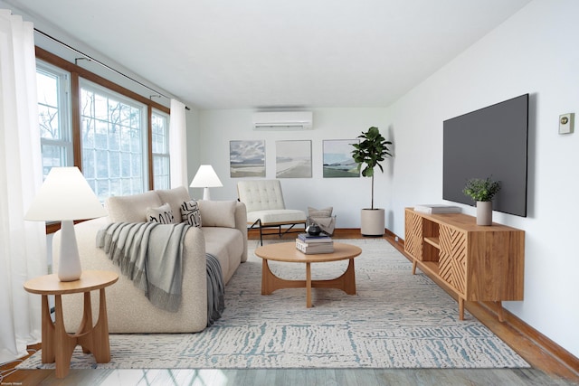 living room featuring a wall mounted air conditioner, baseboards, and wood finished floors