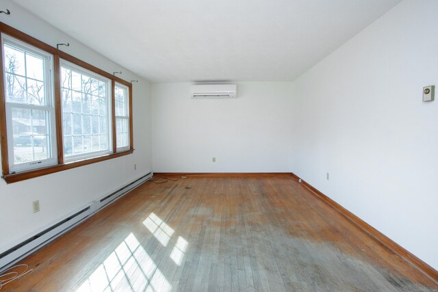 empty room featuring baseboards, a wall unit AC, a baseboard heating unit, and hardwood / wood-style flooring
