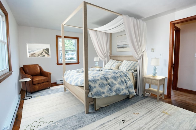 bedroom featuring a baseboard radiator, baseboards, and wood finished floors