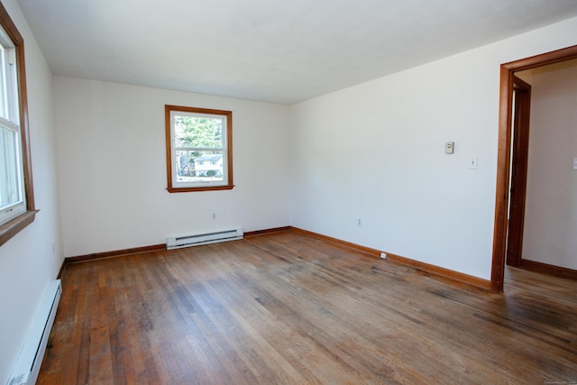 spare room featuring baseboards, a baseboard heating unit, and wood-type flooring