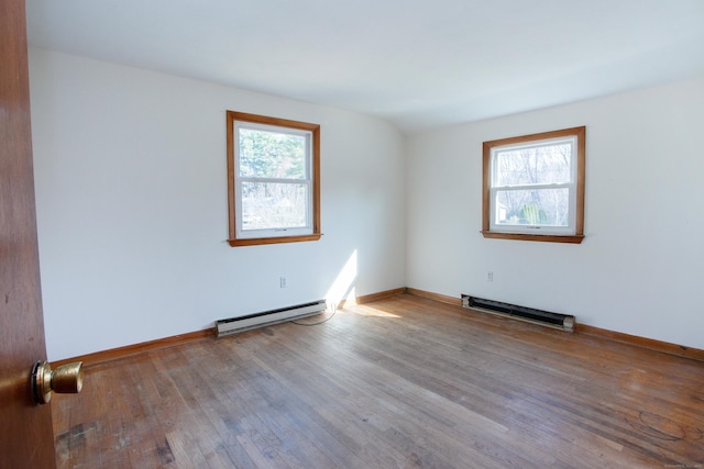 unfurnished room featuring baseboards, wood finished floors, a baseboard heating unit, and a healthy amount of sunlight