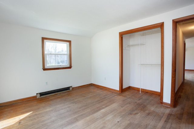 unfurnished bedroom with baseboards, baseboard heating, a closet, and wood finished floors
