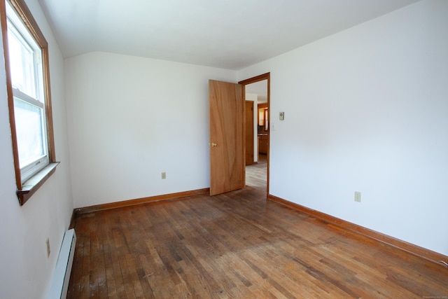 empty room with a wealth of natural light, baseboard heating, lofted ceiling, and hardwood / wood-style flooring