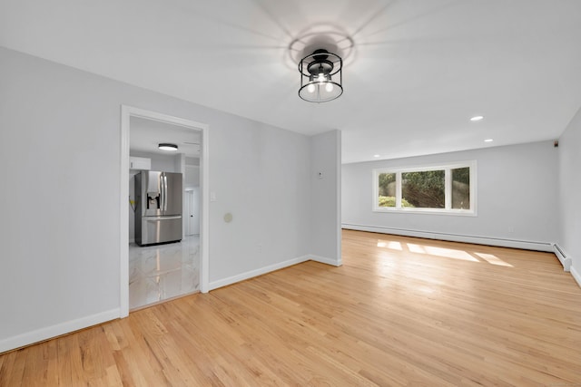 spare room featuring baseboards, recessed lighting, a baseboard heating unit, and light wood-style floors