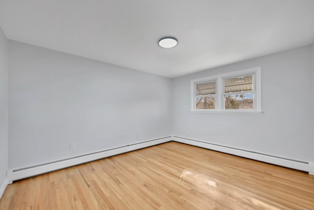 spare room featuring a baseboard heating unit and wood finished floors