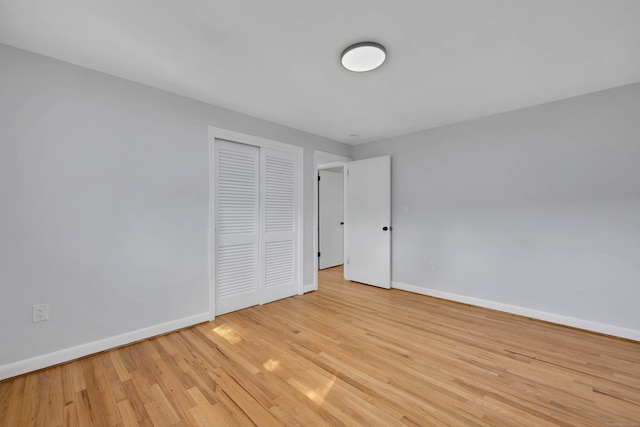 unfurnished bedroom featuring a closet, light wood-type flooring, and baseboards