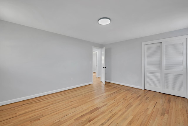 unfurnished bedroom with wood finished floors, baseboards, and a closet