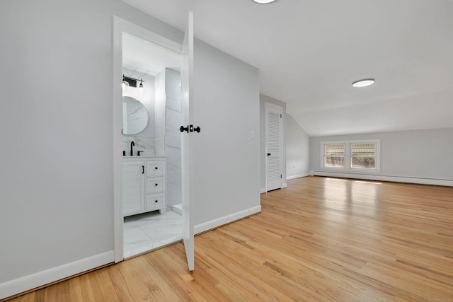 interior space with baseboards, a baseboard radiator, light wood-type flooring, and a sink