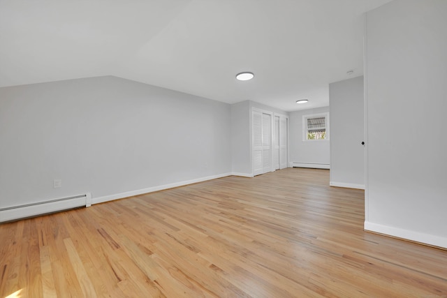 unfurnished room with a baseboard radiator, lofted ceiling, light wood-style floors, and baseboards