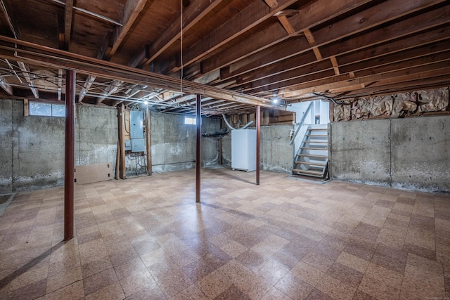 basement featuring tile patterned floors, stairs, water heater, and electric panel