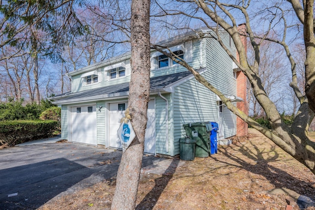 view of front of house featuring a garage, aphalt driveway, and a shingled roof