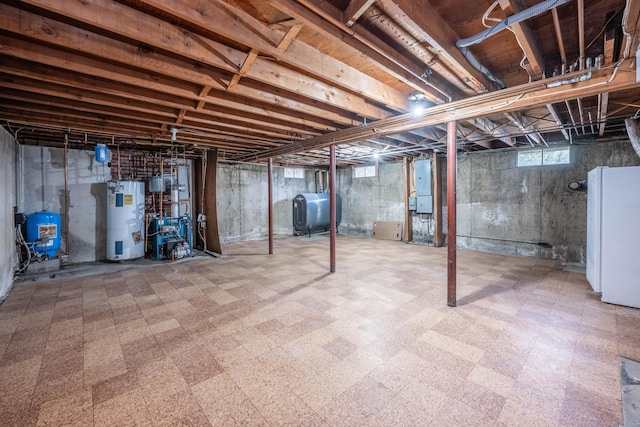 basement featuring tile patterned floors, freestanding refrigerator, heating fuel, and water heater