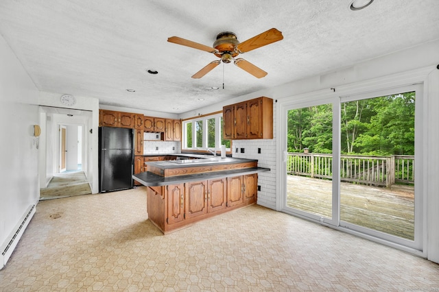 18 Hillcrest Dr, Somers, CT 06071 - kitchen with freestanding refrigerator, a baseboard heating unit, brown cabinetry, a peninsula, and dark countertops