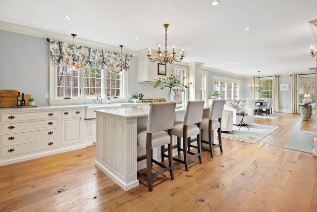 kitchen with light wood finished floors, crown molding, and a chandelier