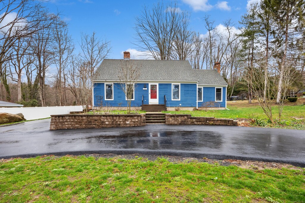view of front facade featuring fence, roof with shingles, a chimney, and a front lawn
