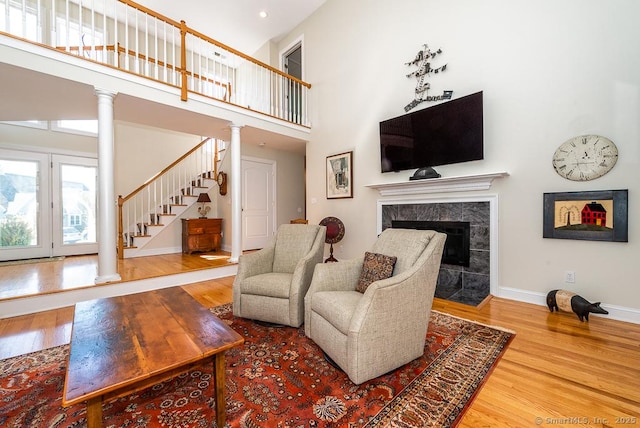 88 Sconset Ln, Guilford, CT 06437 - living area with a fireplace, stairway, a high ceiling, decorative columns, and wood finished floors