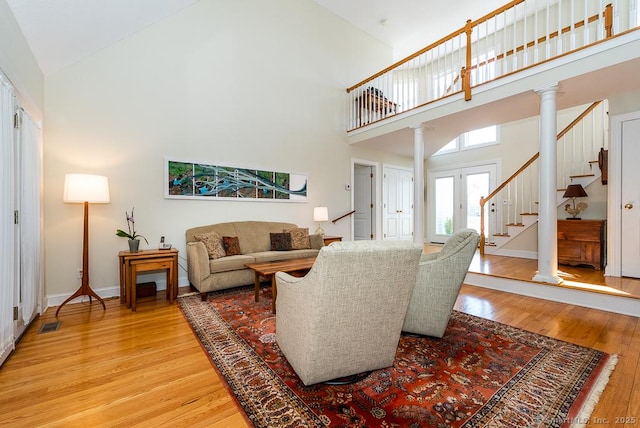 88 Sconset Ln, Guilford, CT 06437 - living area with high vaulted ceiling, ornate columns, light wood-style floors, and stairs