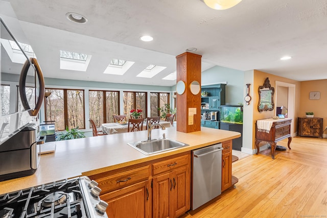 20 Sunrise Trl, East Lyme, CT 06333 - kitchen with dishwasher, a skylight, range with gas cooktop, a sink, and brown cabinetry