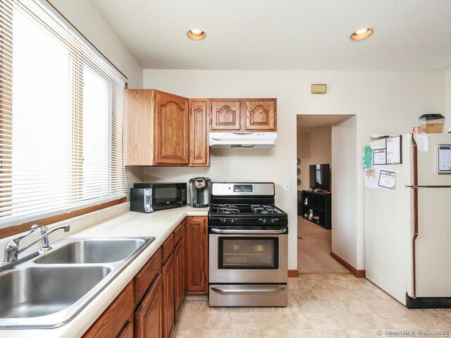 17-19 Fenwick St, Hartford, CT 06114 - kitchen featuring freestanding refrigerator, gas range, under cabinet range hood, a sink, and brown cabinetry