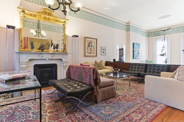 living area featuring a fireplace, a notable chandelier, wood finished floors, and crown molding