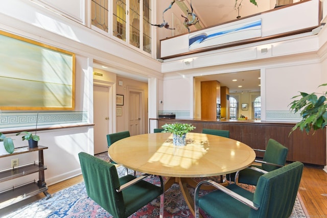 dining space with a towering ceiling and wood finished floors