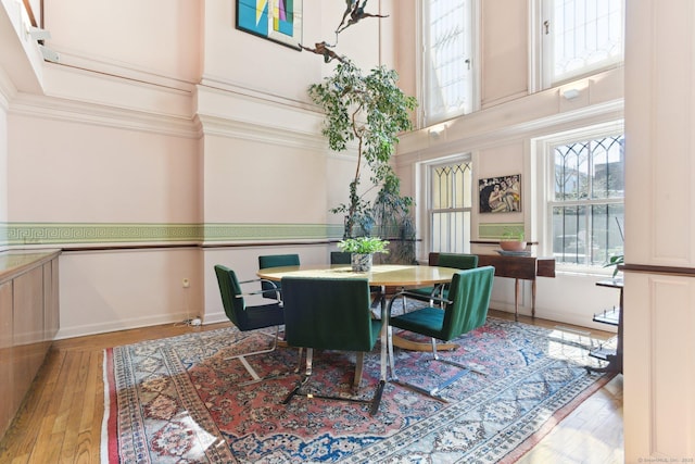 dining room featuring baseboards, a high ceiling, and hardwood / wood-style flooring