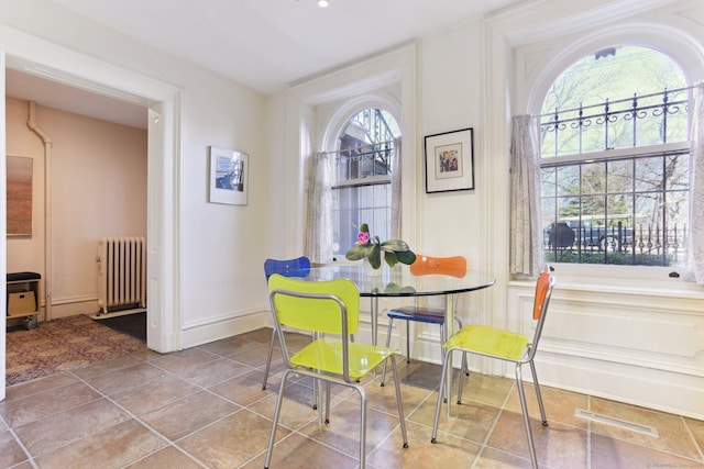 tiled dining space with radiator heating unit and visible vents
