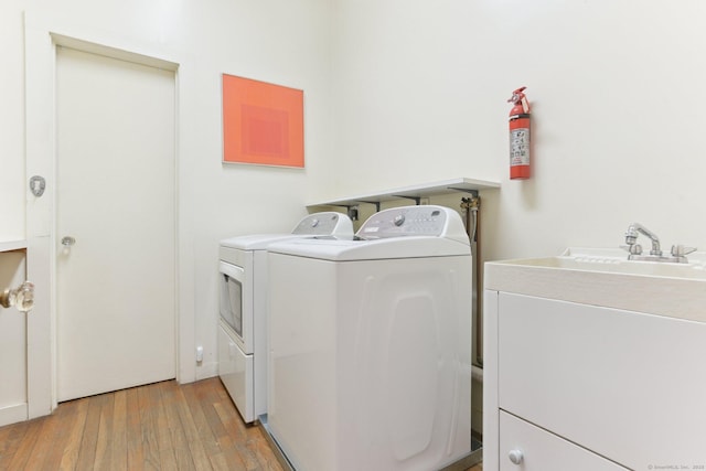 clothes washing area featuring laundry area, separate washer and dryer, and light wood finished floors