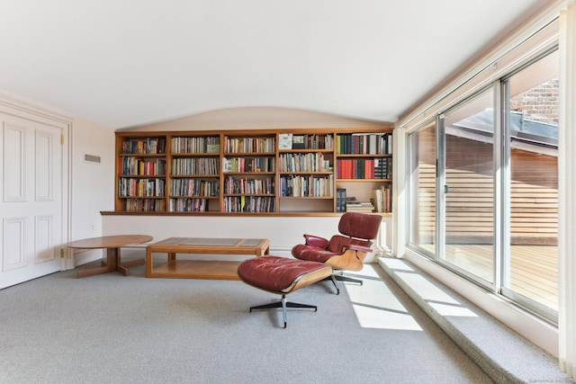 living area with carpet flooring, a healthy amount of sunlight, and lofted ceiling