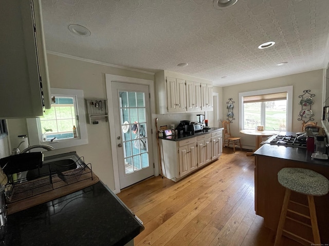 kitchen featuring crown molding, dark countertops, plenty of natural light, and light wood-type flooring