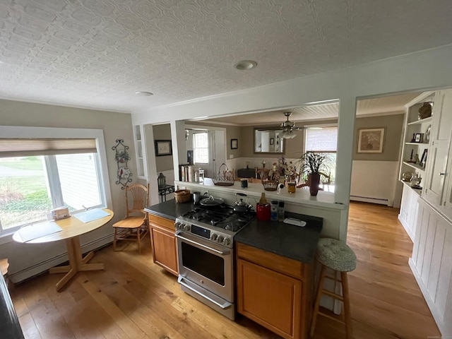 kitchen with a baseboard heating unit, light wood finished floors, gas range, and brown cabinetry