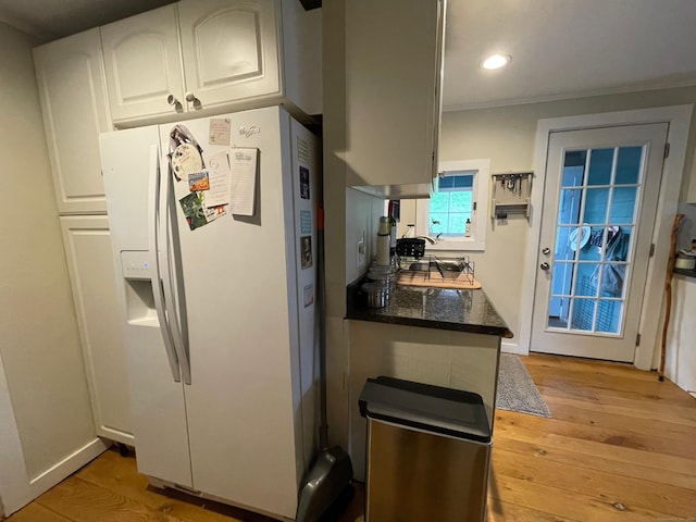 kitchen with dark stone countertops, white cabinets, white refrigerator with ice dispenser, light wood-style floors, and recessed lighting