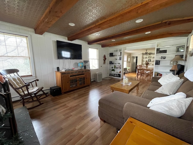 living area featuring a baseboard radiator, wood finished floors, recessed lighting, and beamed ceiling