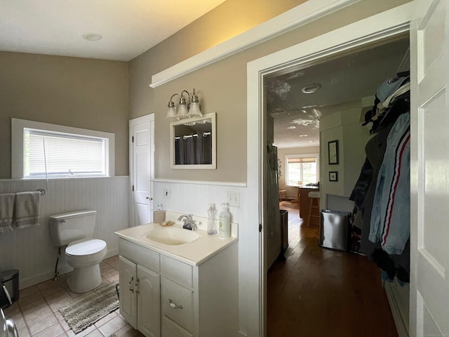 bathroom with toilet, vanity, and a wainscoted wall